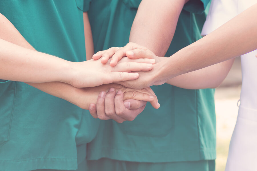 Care team joining hands in a gesture of support